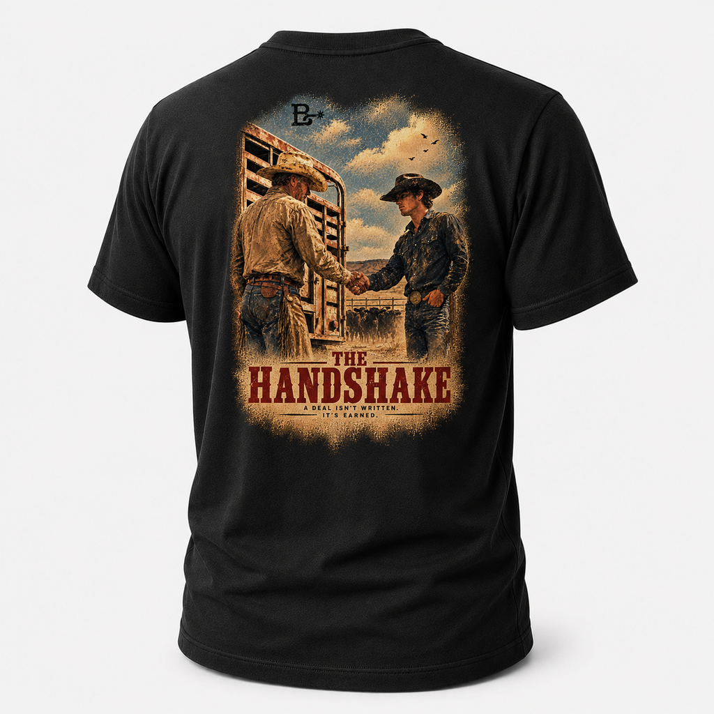 Black The Handshake Western Values T-shirt, back view featuring an older rancher and younger cowboy sealing a deal by the sto